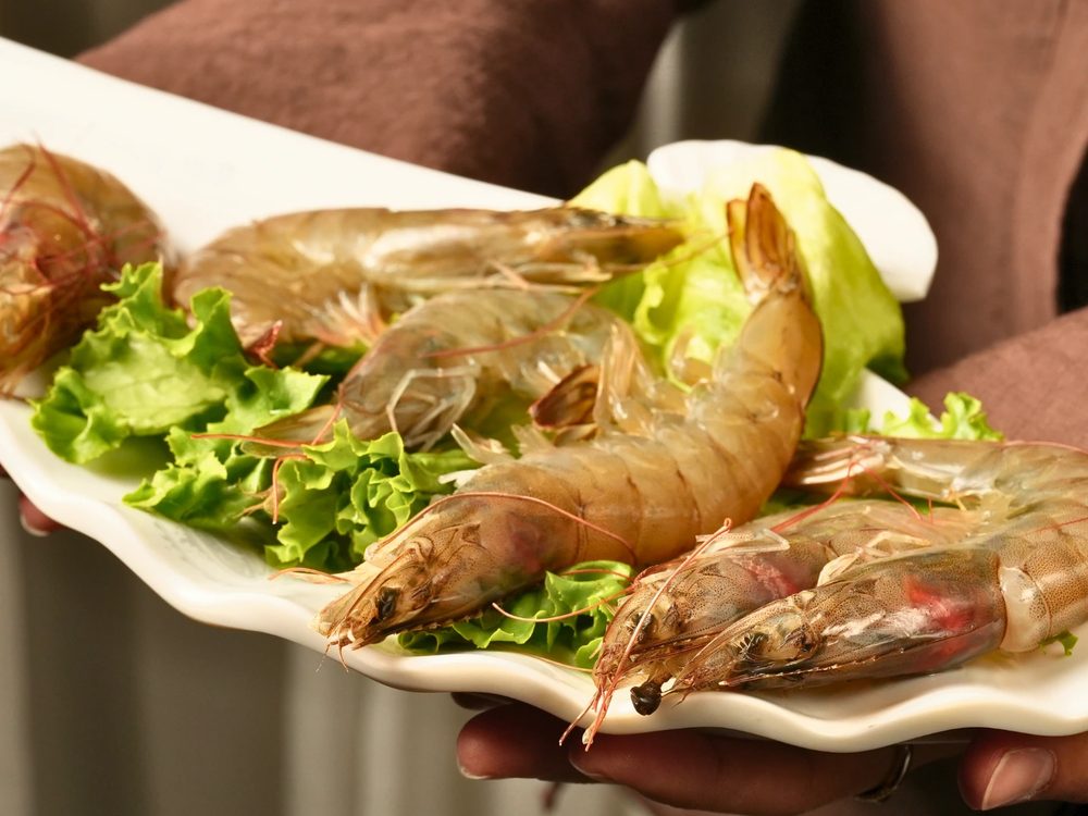 A platter of whole white shrimp on lettuce