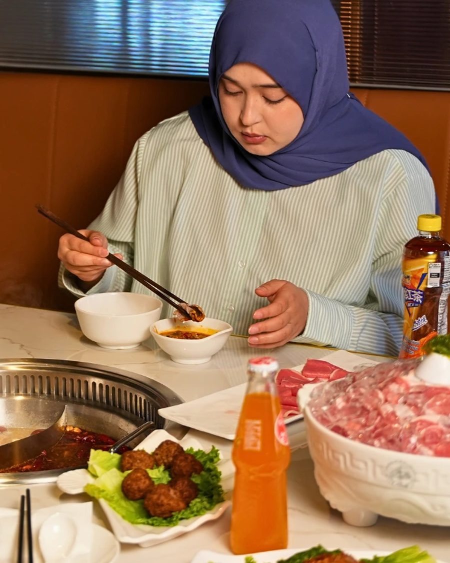 A guest choosing sliced meat at her table at Otluk Hot Pot